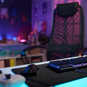 powerwalker_ups_dla_graczy_streaming Stanowisko gracza z biurkiem, krzesłem, klawiaturą, myszką, padem do konsoli oraz neonowo rozświetlonym pokojem na 2 planie.